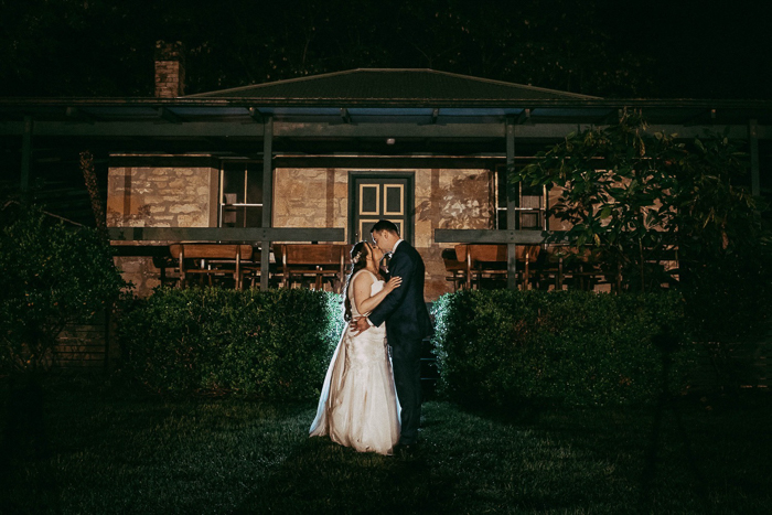Bride and Groom kissing at night in front of building